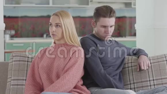 一对沮丧的高加索夫妇背靠背坐在沙发上思考的肖像伤心的年轻女人和男人争论视频的预览图