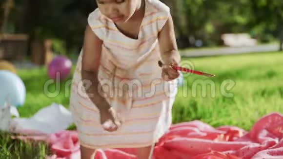 小非洲女孩正在公园里玩画笔和记号笔背景上有五颜六色的气球视频的预览图