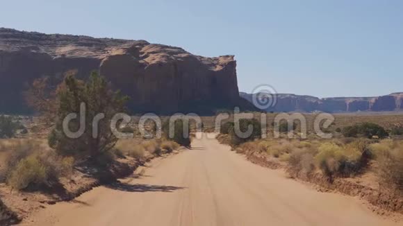 在沙漠中的沙漠中在红岩中驾驶尘土飞扬的泥土路视频的预览图