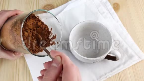 用勺子从玻璃瓶中取出干可可粉放入杯中棕色天然成分烹饪制作热巧克力特写镜头视频的预览图