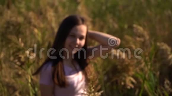 漂亮的年轻女孩的肖像穿着粉红色的t恤在田野里看着镜头失去焦点然后集中慢慢视频的预览图
