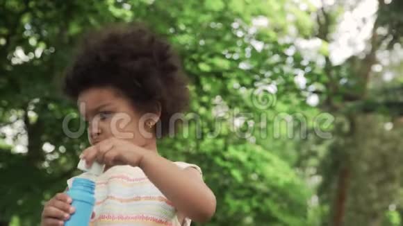 又小又可爱的非裔美国女孩在公园里吹肥皂泡视频的预览图