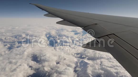 从天空中的飞机窗口看天空和山脉中的雪和云视频的预览图