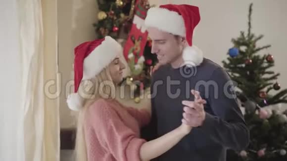 白人男女在家中新年树前跳舞的特写镜头圣诞快乐的年轻夫妇视频的预览图