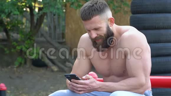 健美运动员使用智能手机小胡子运动健美运动员在户外运动视频的预览图