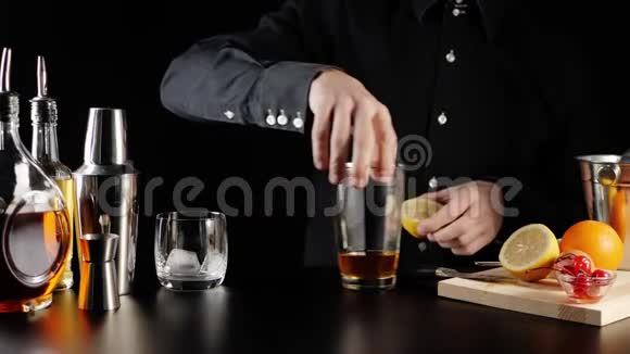 威士忌酸鸡尾酒酒保拿了半个黄色多汁的柠檬把柠檬里的汁挤成金属夹钳视频的预览图