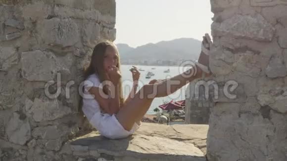 坐在古石墙上的酷爱快乐的女孩视频的预览图