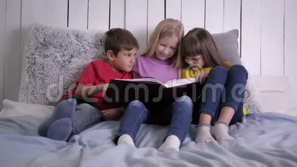 家庭教育聪明可爱的小孩子坐在床上做作业和看书视频的预览图