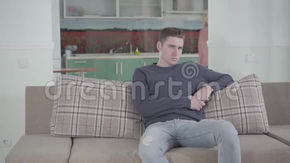 年轻英俊的白人男子坐在沙发上作为他的女朋友或妻子来自背景和责骂的肖像视频的预览图