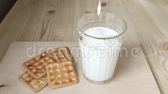 凯菲酸牛奶或白色饮用酸奶倒入玻璃发酵乳制品特写木桌干饼干视频的预览图