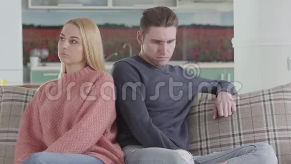 悲伤的高加索男人和女人坐在沙发上女孩用肩膀推配偶有关系的夫妻视频的预览图