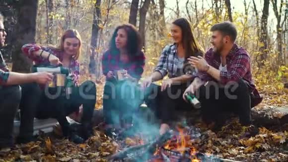 秋天的森林里坐在火堆旁的年轻游客视频的预览图