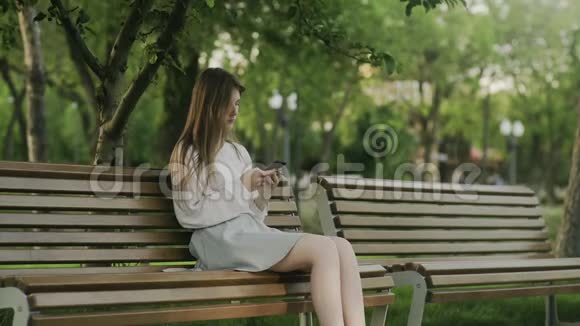 坐在公园里坐轮椅的年轻人和坐在长凳上悲伤地看着他视频的预览图