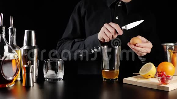 威士忌酸鸡尾酒酒保拿起一把刀打碎鸡蛋用波旁威士忌把鸡蛋溅到玻璃杯里视频的预览图