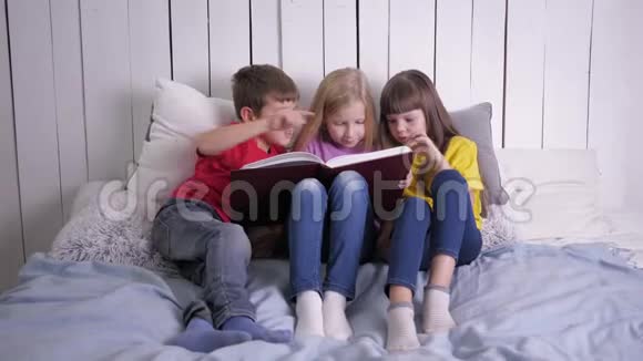 教育穿着多色衣服的聪明孩子学会在家里坐在沙发上看书视频的预览图