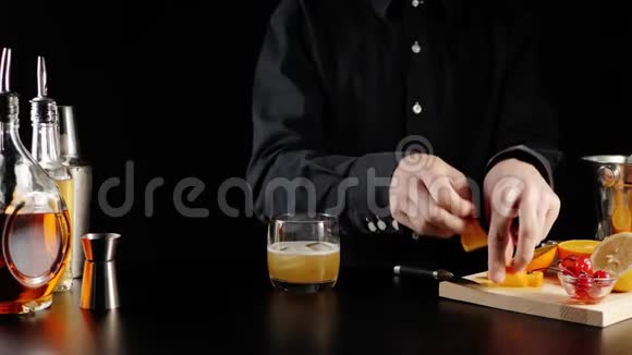 威士忌酸鸡尾酒酒保拿了一片橘子放在一个带有威士忌酸鸡尾酒的石头玻璃里装饰视频的预览图