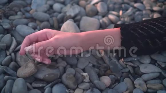 一个年轻的女孩躺在海边没有知觉没有动作一个女孩的手躺岩石海岸上的特写镜头视频的预览图