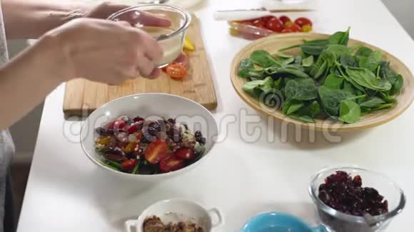 覆盆子维奈格雷特沙拉酱准备蔬菜沙拉沙拉原料菠菜西红柿蓝奶酪的女人视频的预览图