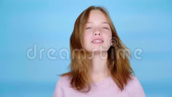 穿着粉红色套头衫的快乐少女微笑着手里拿着一把梳子说话视频的预览图