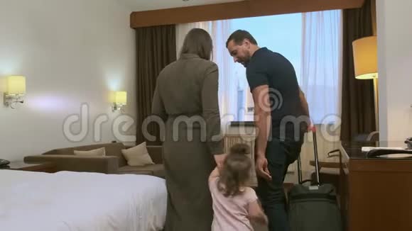 一家人带着手提箱进入旅馆房间视频的预览图