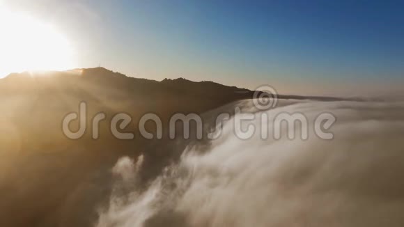 无人机照相机飞过蓬松的云层和阳光照耀的山顶视频的预览图