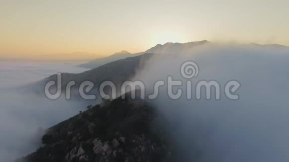 在山景中用雾和云在森林上的空中俯瞰视频的预览图