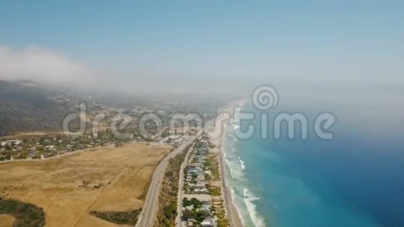 从空中俯瞰道路汽车田野海滩房屋海岸海浪蓝色海洋和一片峡谷视频的预览图