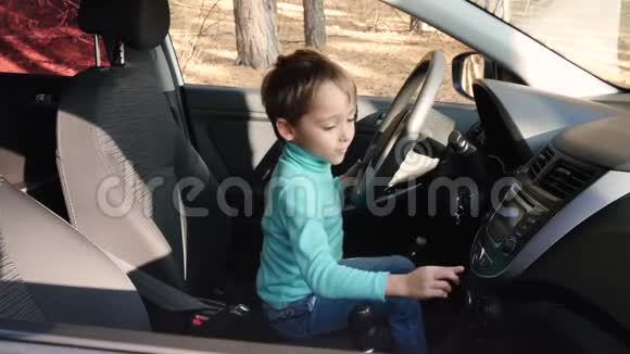 一个快乐的孩子坐在汽车的驾驶座上玩耍想象自己是个司机那个男孩转动方向盘视频的预览图