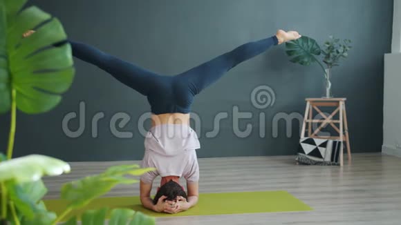 一位身材苗条的瑜伽教练在工作室做倒立时的慢速后视视频的预览图