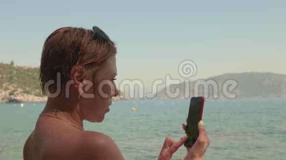 旅游妇女拍摄海洋到手机用智能手机拍摄海上某物的成年女性晒黑视频的预览图