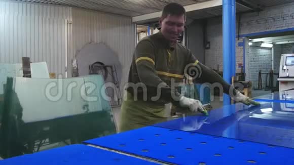 一个工人在一张蓝色的桌子上切玻璃并把它放在柜台上浮玻璃视频的预览图