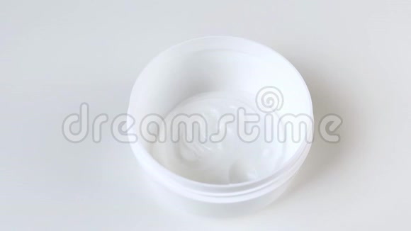 奶油倒入塑料圆罐中润肤露居家养身补水特写镜头白色背景视频的预览图