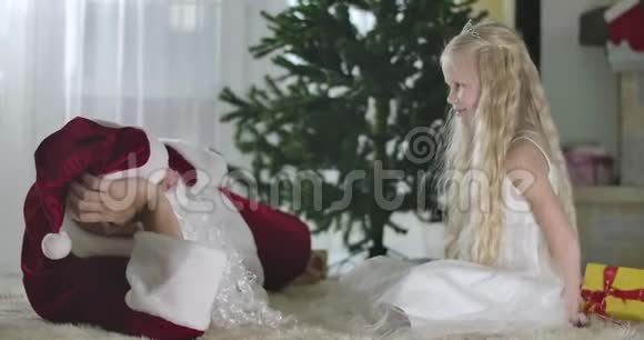 快乐的白人女孩卷发送礼物给穿圣诞老人服装的男人可爱的儿童礼物视频的预览图