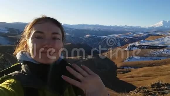 开朗的旅行者深色头发的女人在白雪覆盖的埃尔布鲁斯山的背景下自拍光明的高加索之旅视频的预览图