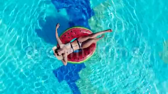 一个女人在游泳池里放松时漂浮在橡胶圈上视频的预览图