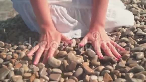 一个女人的特写她的手捡起一块石头然后把它从海滩上的手掌上扔了出来视频的预览图