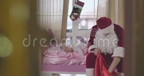 圣诞老人拿出圣诞礼物放在粉红色的枕头上可爱的女孩正在睡觉圣诞老人离开视频的预览图