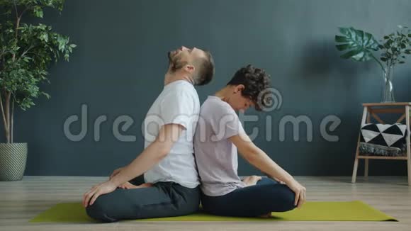男女练习双人瑜伽在工作室的垫子上做热身运动视频的预览图