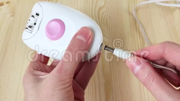 将电线插入设备白色扩张器女性的手打开电动小工具来去除头发特写木制背景视频的预览图
