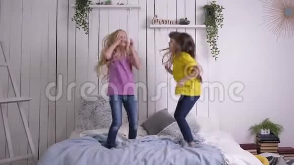 留着长发的快乐小女朋友在家里休息的时候在床上慢动作地跳着玩视频的预览图