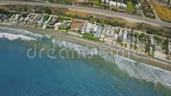 海岸附近有房子的蓝色海洋的空中镜头山脚下有过往的汽车视频的预览图