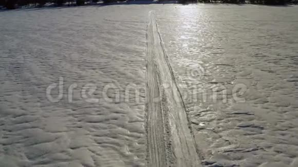 一个面目全非的人在冰冻的湖面上的旧雪上滑雪得很快非常晴朗平静的一天直接无人机飞行视频的预览图