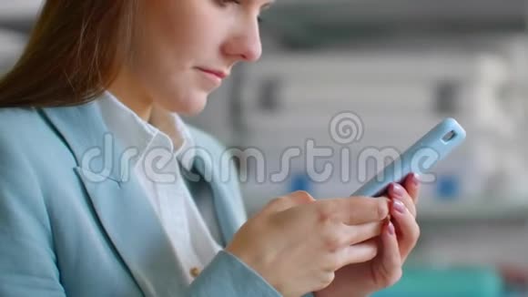 特写一位年轻的女士穿着西装设计师在缝纫车间里穿着带手机的裁缝工作室视频的预览图