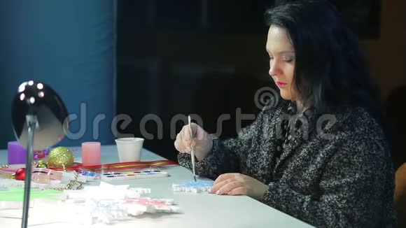 在一个冬天的晚上一个年轻的女人用蓝色的水彩画雪花为圣诞节做家居装饰视频的预览图