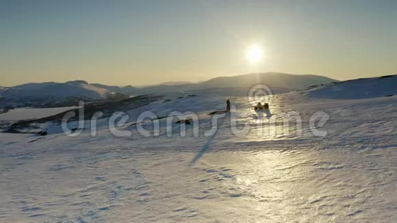 无人机在一个独立的人身上低飞雪车在日落前朝金色太阳飞去冬天的群山视频的预览图