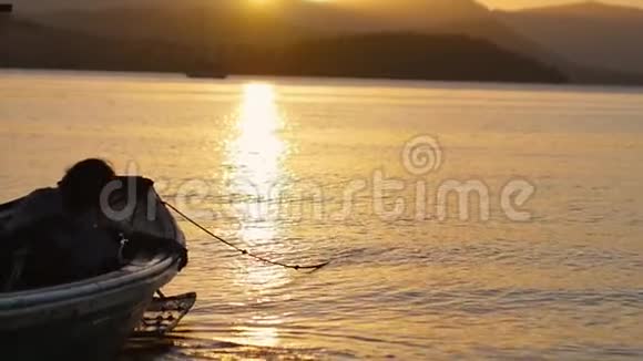 黎明时在平静的海面上的渔夫的剪影美丽的日落海上有一艘渔船的轮廓视频的预览图