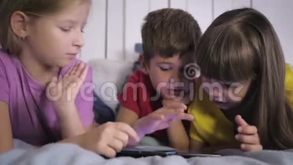 孩子们学习现代技术穿着多色衣服的小伙伴在家里躺在床上视频的预览图
