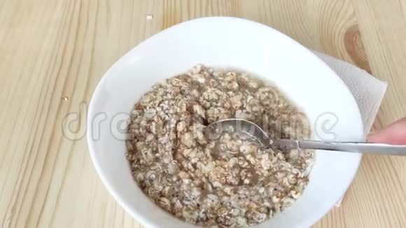 在水中酿造粥用勺子混合白色碗中的真薄片黑麦小麦大麦燕麦快速烹饪健康食品视频的预览图