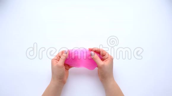 在白色背景上玩粉红色黏液的女人的手时髦的液体玩具俯视图视频的预览图