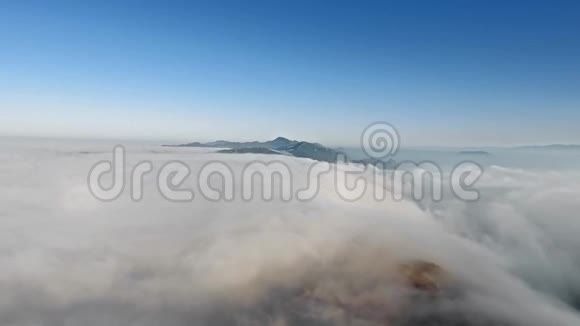 无人机相机在清晨拍摄无穷无尽的厚厚云层和突出的山峰视频的预览图